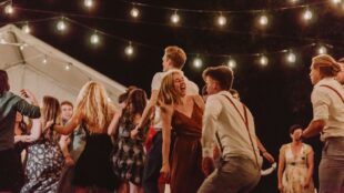 Människor dansar under ljusslingor vid en utomhusfest
