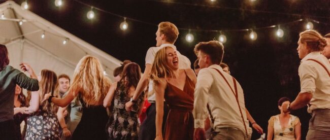 Människor dansar under ljusslingor vid en utomhusfest