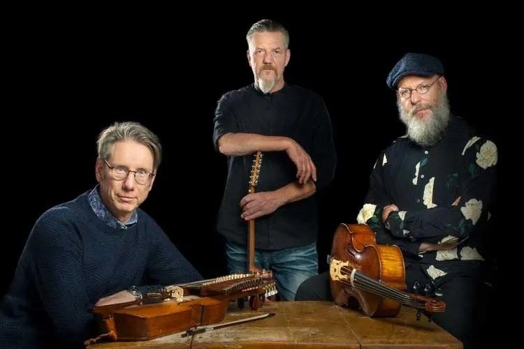 Tre musiker med traditionella stränginstrument framför svart bakgrund